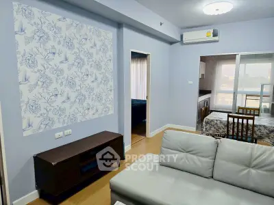 Modern living room with floral accent wall and open view to dining area, featuring sleek furniture and air conditioning.