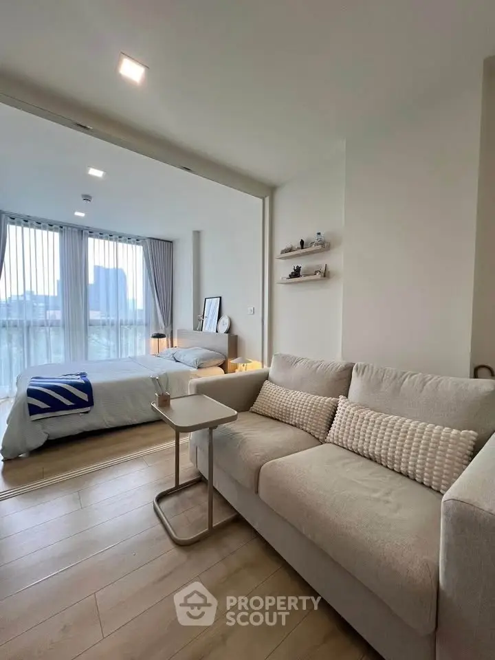 Modern open-plan living room and bedroom with stylish decor and large windows.