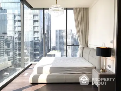 Luxurious bedroom with floor-to-ceiling windows offering panoramic city views, complemented by a chic chandelier and modern furnishings.