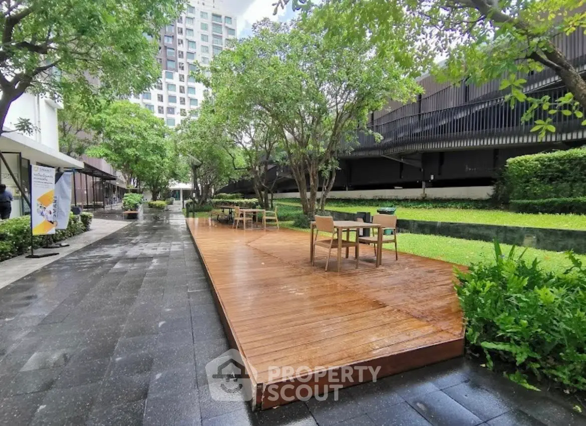 Charming garden area with wooden deck and seating in modern residential complex.