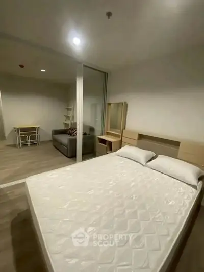 Modern bedroom with glass partition and cozy living area in a stylish apartment.