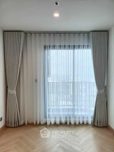 Elegant room with floor-to-ceiling window and sheer curtains offering a stunning city view.