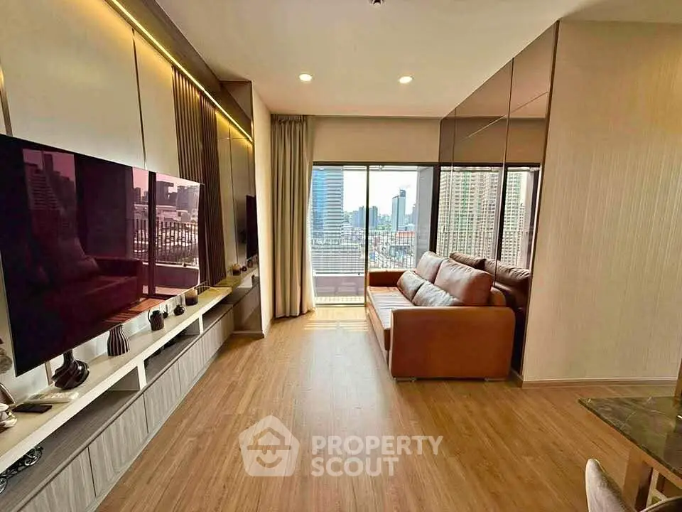 Modern living room with large TV, leather sofa, and city view from balcony.