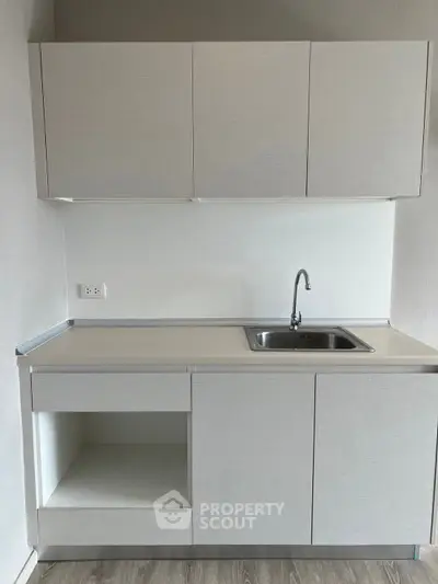 Modern minimalist kitchen with sleek cabinetry and stainless steel sink, perfect for contemporary living.