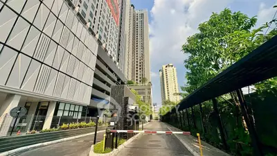 Modern high-rise building with lush greenery and secure entrance in urban setting.