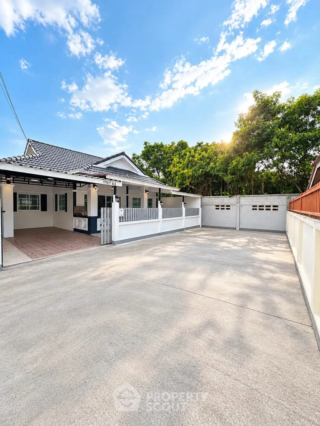 Charming single-story home with spacious driveway and lush greenery, perfect for family living.