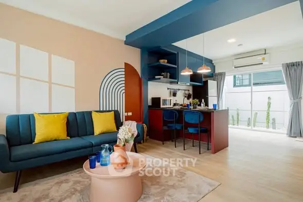 Stylish modern living room with open kitchen and vibrant decor in a bright apartment.