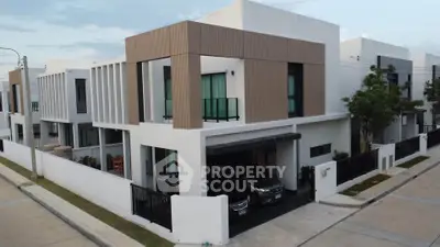 Modern two-story house with sleek design and spacious driveway in a suburban neighborhood.