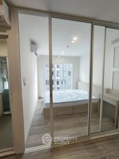 Modern bedroom with large windows and sliding glass doors in a stylish apartment.