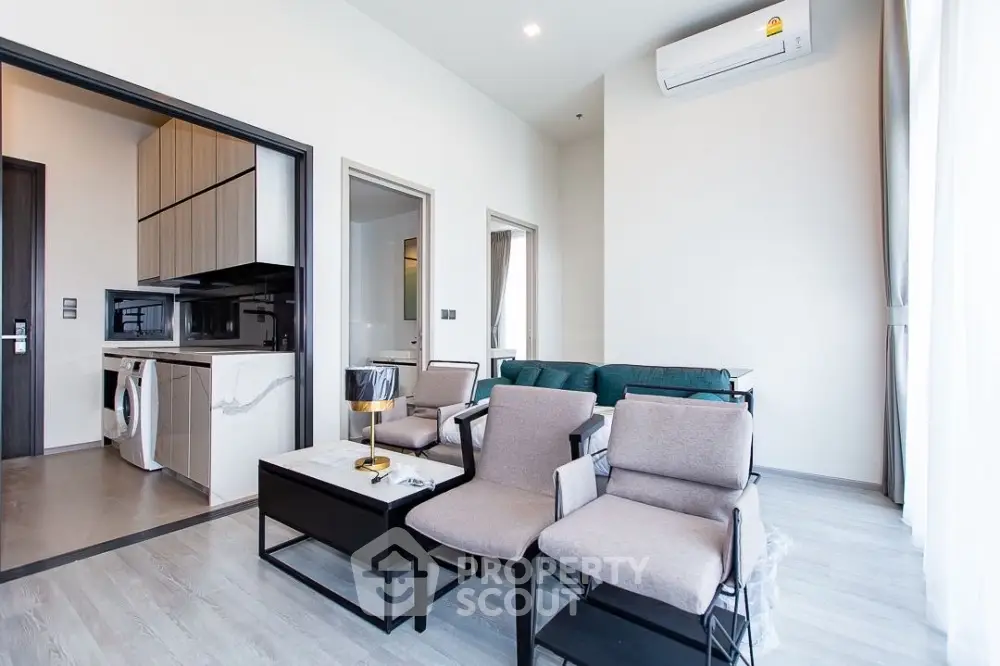 Modern living room with sleek furniture and open kitchen layout in a bright apartment.
