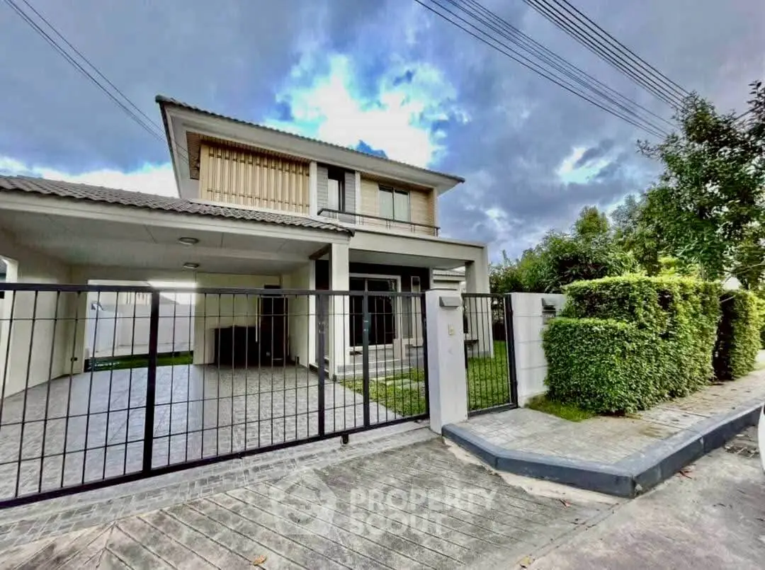 Modern two-story house with gated driveway and lush greenery, perfect for family living.