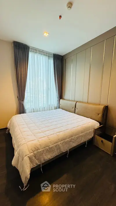 Spacious bedroom with elegant decor and large window offering natural light.