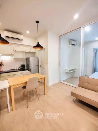 Modern open-plan living room with kitchen, featuring sleek design and ample natural light.