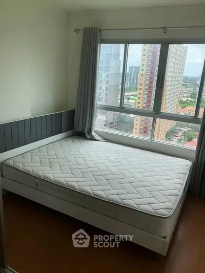 Bright bedroom with large window offering city view and modern decor.