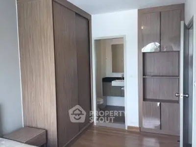 Modern bedroom with wooden wardrobe and ensuite bathroom in stylish apartment.