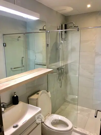 Modern bathroom with glass shower and sleek fixtures in contemporary home.