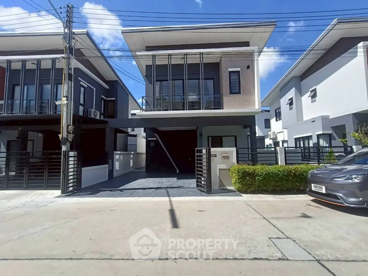 Modern two-story house with sleek design and spacious driveway in a suburban neighborhood.