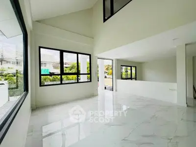 Spacious modern living room with large windows and glossy white flooring