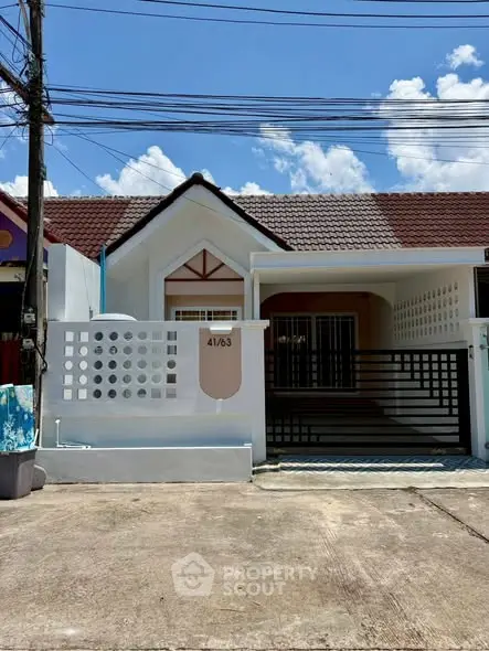 Charming single-story house with a tiled roof and gated driveway, perfect for cozy living.