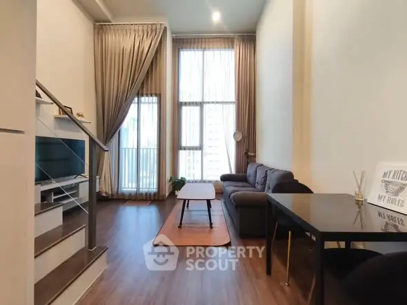 Modern living room with high ceilings and large windows in a stylish apartment.