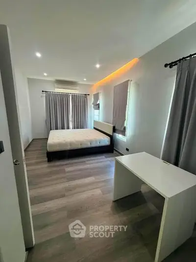Modern bedroom with stylish decor and natural light, featuring a comfortable bed and sleek flooring.