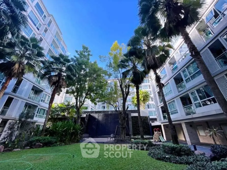 Modern apartment building with lush garden and palm trees, perfect urban oasis.