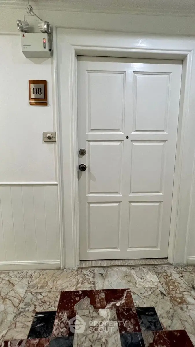 Elegant apartment entrance with white door and marble flooring, showcasing a sophisticated entryway.