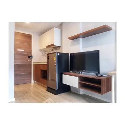 Modern apartment interior with sleek kitchen and cozy living area featuring a flat-screen TV and stylish shelving.