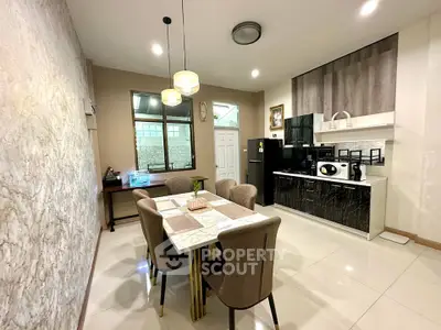 Modern kitchen with dining area, sleek appliances, and elegant lighting in a stylish home.