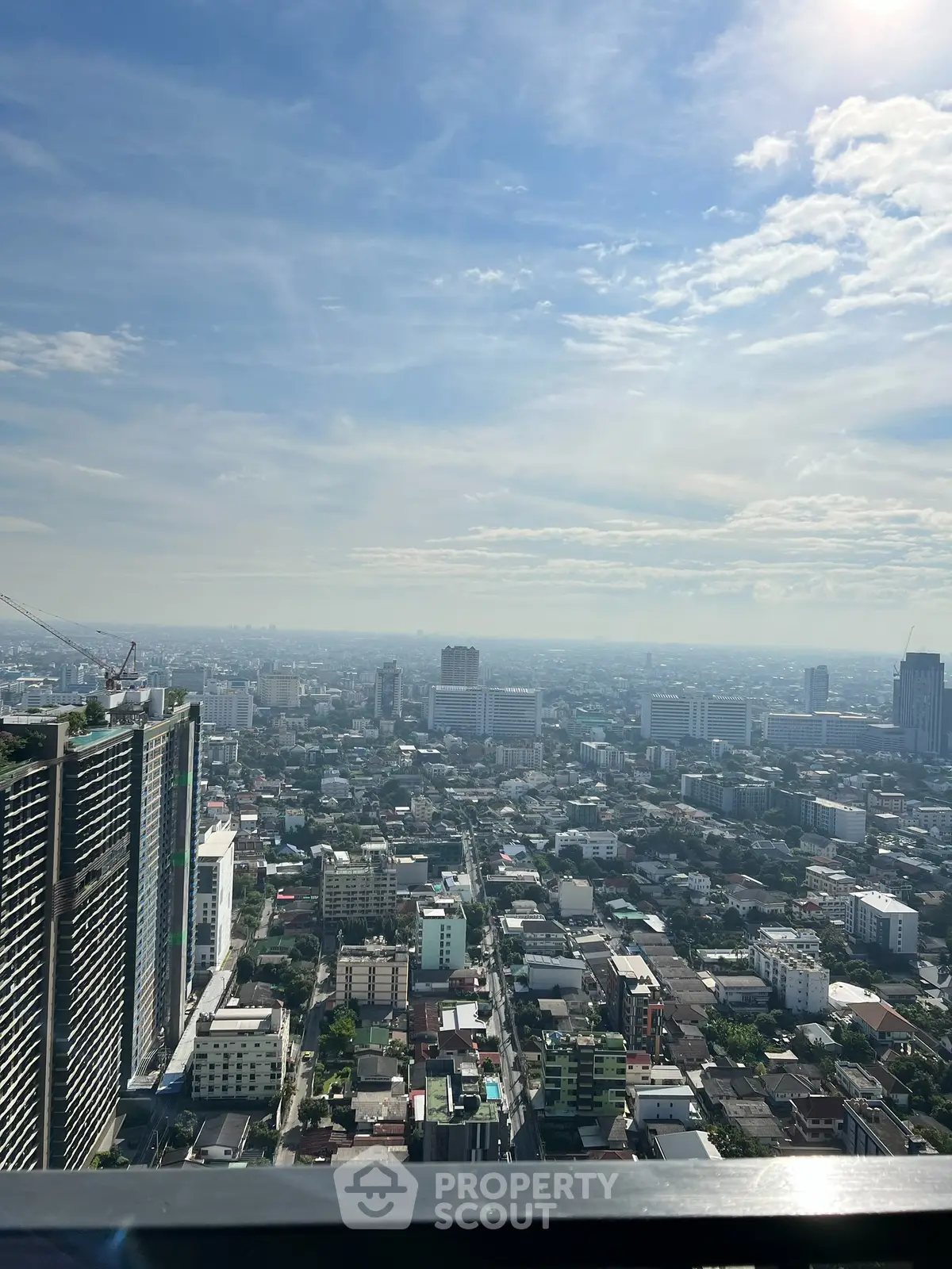Stunning cityscape view from a high-rise building balcony, showcasing urban skyline under a clear blue sky.