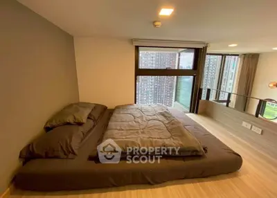 Modern bedroom with large window offering stunning city view in high-rise apartment.