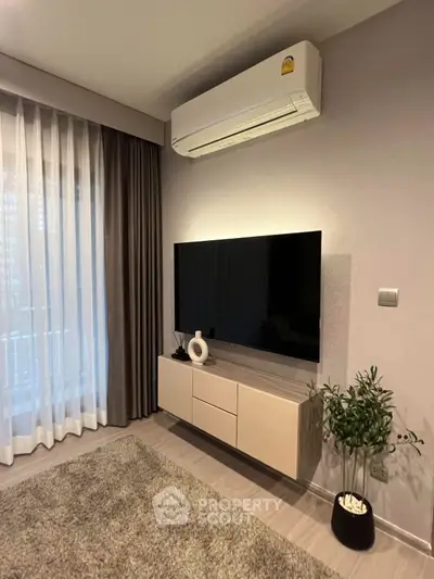 Modern living room with sleek TV setup and air conditioning, featuring elegant curtains and a cozy rug.