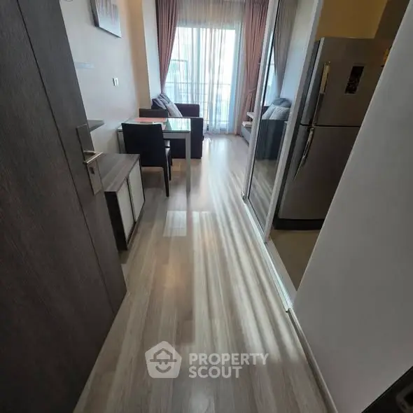 Modern apartment hallway leading to a cozy living area with natural light and sleek furnishings.