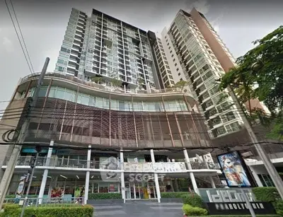 Modern high-rise condominium with retail shops at the base, showcasing urban living in a vibrant cityscape.