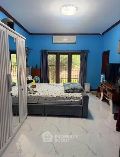 Spacious bedroom with modern decor and large windows for natural light.