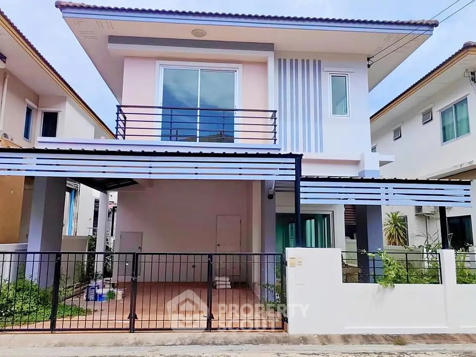 Modern two-story house with balcony and gated entrance in a suburban neighborhood.