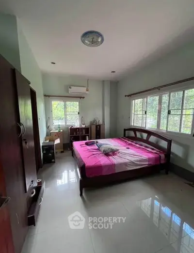 Spacious bedroom with large windows and modern furnishings, perfect for comfort and relaxation.