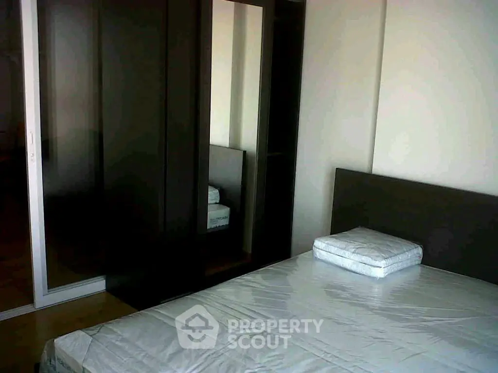 Modern bedroom with sleek dark wardrobe and minimalist bed setup.
