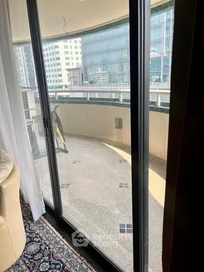 Spacious balcony with city view from modern apartment, featuring large glass doors and elegant flooring.