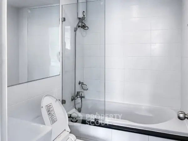 Modern bathroom with glass shower and bathtub in sleek white design.