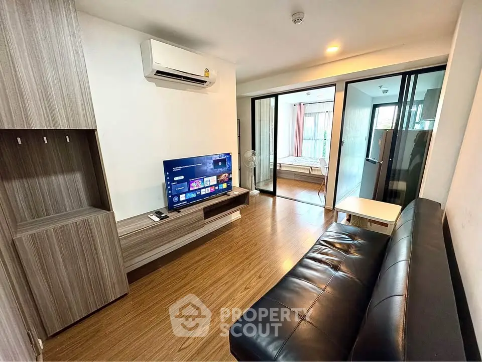 Modern living room with sleek design, featuring a leather sofa, wall-mounted TV, and air conditioning.