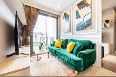 Stylish living room with green sofa and modern decor, featuring large windows and balcony access.