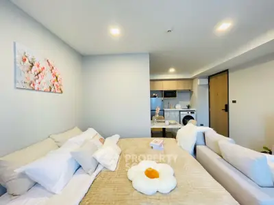 Modern living room with cozy decor and open kitchen layout in stylish apartment.