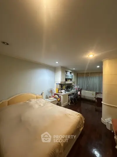 Cozy bedroom with integrated kitchen area, featuring warm lighting and wooden flooring.