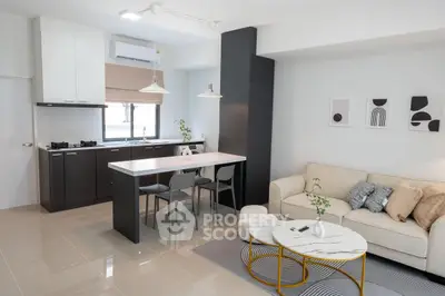 Modern open-layout living room and kitchen with sleek design and cozy furnishings.
