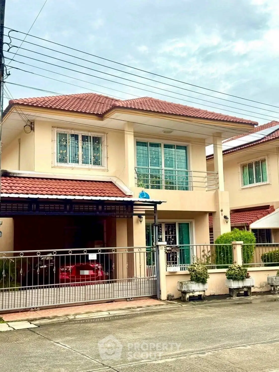 Charming two-story house with red tile roof and gated driveway in suburban neighborhood.