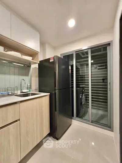 Modern kitchen with sleek appliances and sliding glass door for natural light.