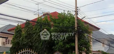 Charming suburban house with red roof and lush greenery, perfect for family living.
