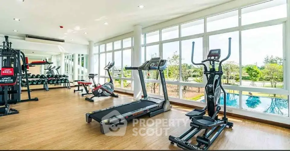 Spacious gym with modern equipment and pool view in luxury real estate property.
