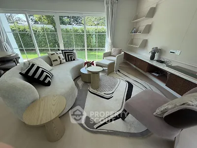 Luxurious living room with modern furniture and large windows overlooking a lush garden.